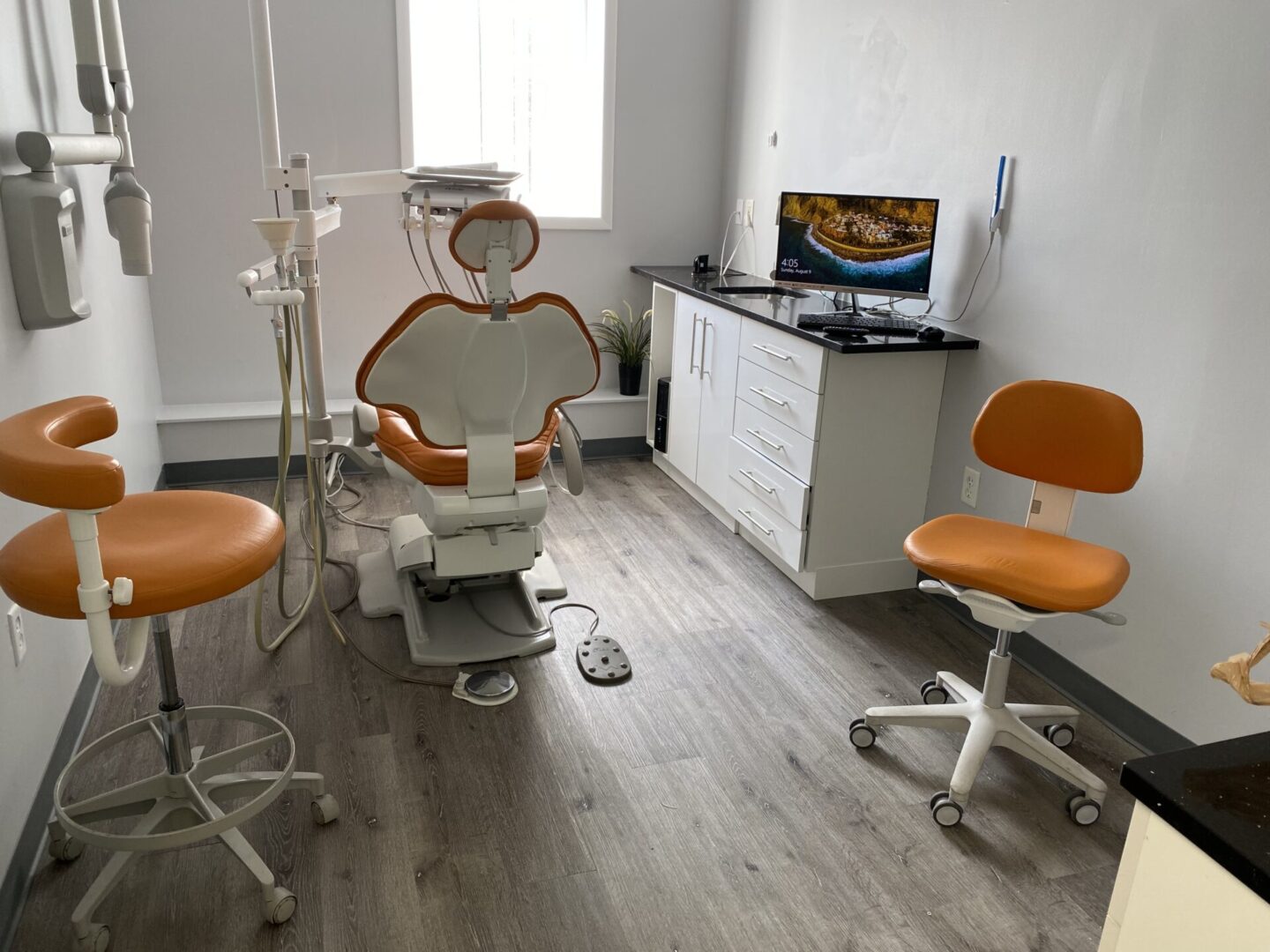 A dentist 's office with orange chairs and white walls.