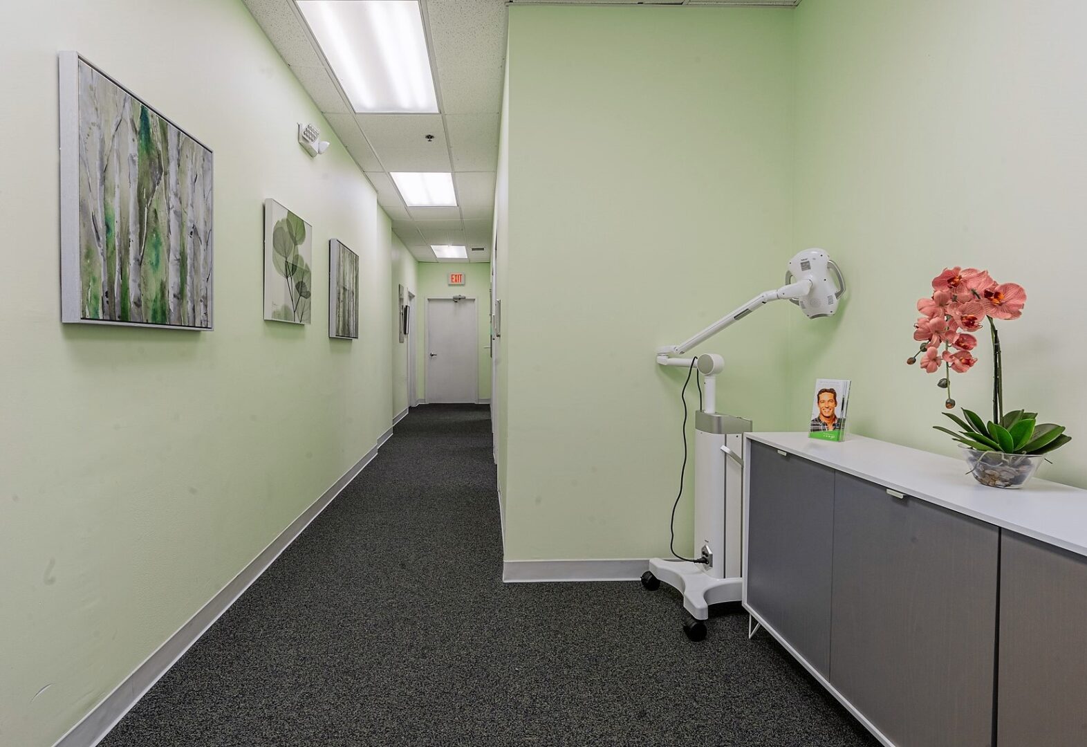 A hallway with a light green wall and a white floor.